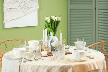 Table setting with tulip flowers for International Women's Day celebration in stylish room near green wall