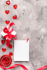 Composition with gift box, blank paper sheet and hearts for Valentine's Day celebration on grey...