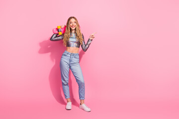 Stylish young woman posing with a pink skateboard against a vibrant pink background