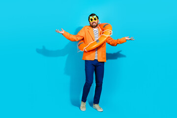 Fototapeta premium Charming young man in vibrant attire with a lifebuoy posing playfully against a turquoise background.