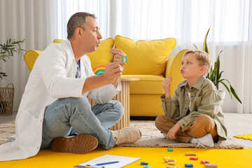 Male speech therapist with little boy pronouncing letter U in office