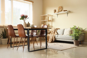 Interior of dining room with table, sofa and protea flowers in vases