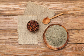 Bowls with anise, dried seeds and spoon on wooden background