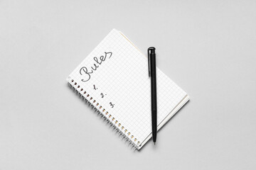 Notebook with blank list of rules on light background