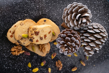 Pine nut cookies on black and white background with pine cones next to them kitchen concept