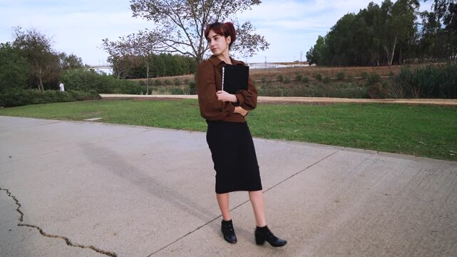 Chica joven atravesando un parque de camino al instituto o la universidad.