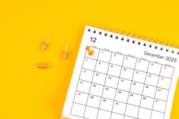 December 2025 Monthly desk calendar for 2025 year with wooden pin on yellow background.