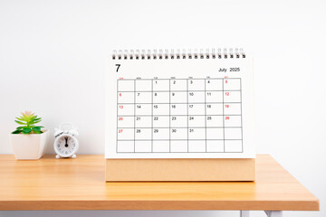 July 2025, Monthly desk calendar for 2025 year on wooden table.