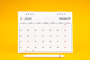 March 2025, Monthly desk calendar for 2025 year and pen on yellow background.