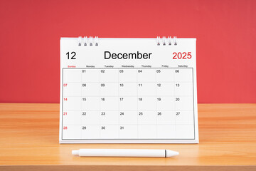 December monthly desk calendar for 2025 year and pen on the wooden table.