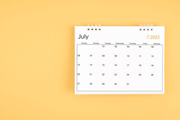 July 2025 desk calendar on yellow color background, position with copy space.
