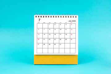 July 2025 desk calendar on blue background.