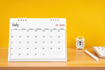 July 2025, Monthly desk calendar for 2025 year on wooden table.