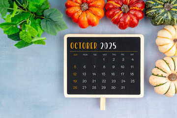 View from above to simple October 2025 calendar decorated with pumpkins.