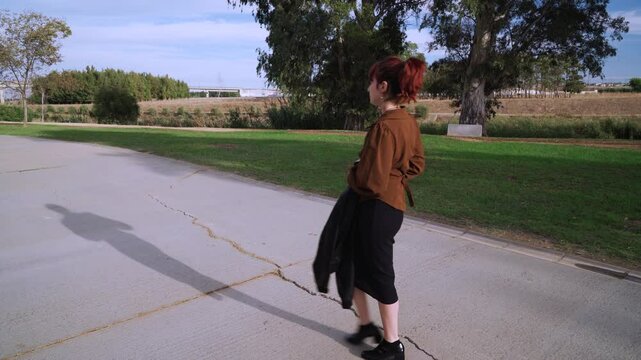 Chica joven millennial atravesando un parque de vuelta del trabajo.
