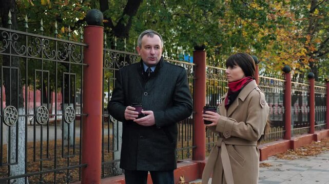 Female worker and male boss discuss company plans drinking coffee. Lady worker discuss company plans with male boss drinking coffee. Discussion of company plans between boss and worker drinking coffee