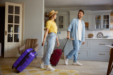 Happy loving couple leaving home with luggage ready for vacation
