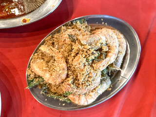 A plate of crispy deep-fried prawns coated in savory oat cereal, butter, curry leaves.