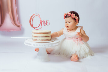 Retrato de una pequeña y alegre cumpleañera con el primer pastel. Comiendo el primer pastel....