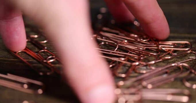 group of copper paper clips for the systematization of documents and paper, large-size copper paper clips close-up on the board