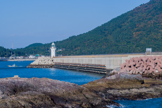White lighthouse on end of concrete pier in Wando, South Korea.