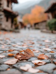 A picturesque cobblestone path lined with autumn leaves, leading through quaint buildings and vibrant fall scenery.