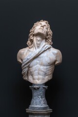 Fototapeta premium Marble bust of a man with his head tilted back, set against a dark background