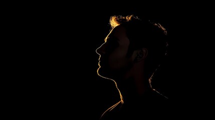 Silhouette of a man's head and shoulders, backlit against a black background, emphasizing shadows