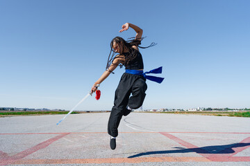 Chica experta en artes marciales haciendo un ataque saltando en el aire, en el paisaje infinito y...