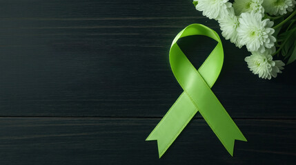 Lime green ribbon represents Mental Health Awareness Month on dark wooden background with white flowers. Symbol of support, hope for mental health. Focus on awareness, campaign for good mental