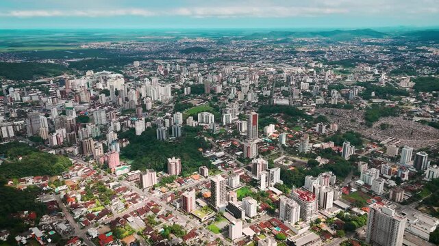 Flight over a medium-sized city, with buildings, houses and green hills
