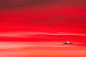 Airplane silhouette against red sunset sky