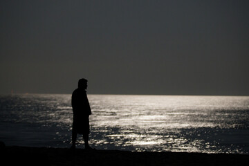 person walking on the beach under the moon