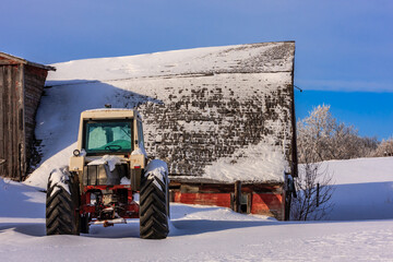 A tractor is parked in front of a red barn