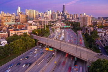 Chicago highway traffic at dusk. Cars blur across the interstate, under a highway overpass, as the...