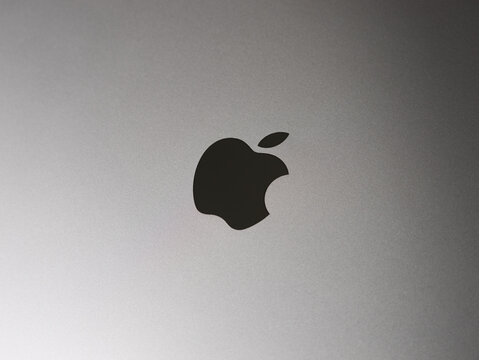 DRESDEN, GERMANY - 30. December 2023: Apple logo sign on a MacBook Pro in the Space Gray. Close up of the dark icon in the aluminum body. High quality technology product from an American company.