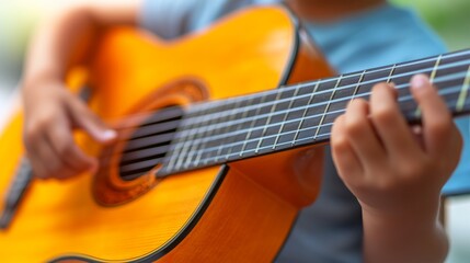 Fototapeta premium Close-up of a child's hands playing an acoustic guitar, focusing on the development of musical talent and skills