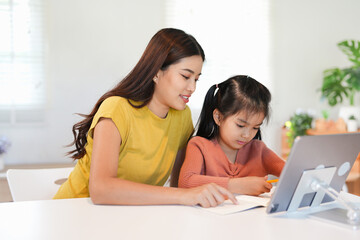 Loving young mum and little preschooler daughter sit at table using laptop tablet together, caring mother help small girl child teaching learning online on computer, kids and technology concept