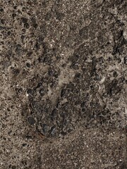 Close-up view of a rough stone surface. The texture is uneven and weathered, with signs of erosion and natural aging.