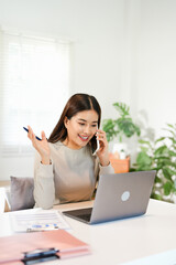 Happy young Asian business woman with a smile using smartphone at the office.