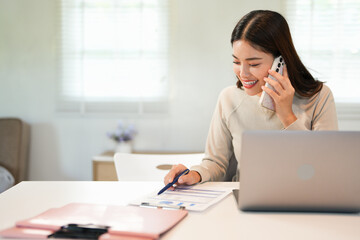 Happy young Asian business woman with a smile using smartphone at the office.