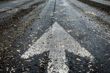 Fototapeta premium Cracked Asphalt Road with Arrow: A study in texture and decay