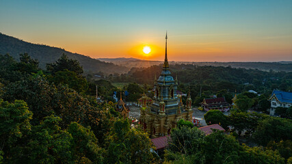 Fototapeta premium Aerial view of Mae Klang Waterfall Temple in Chiang Mai with the sunrise casting warm hues in calm sky. The tranquil setting highlights the serene beauty of the temple and the natural landscape.