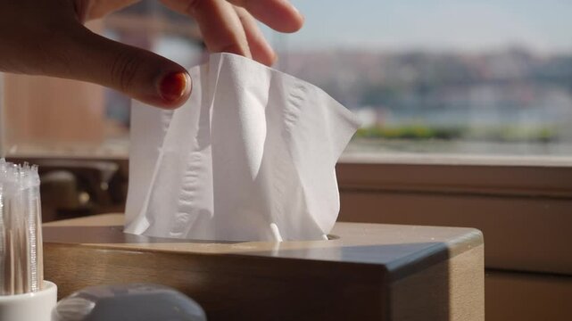  hand pull out a piece of tissue from tissue paper box 