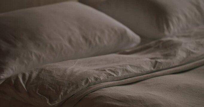 Close-up image showing an unmade bed with rumpled white sheets and pillows, evoking a feeling of warmth and comfort in a personal space. Unmade Bed with Rumpled Sheets in a Cozy Bedroom Setting