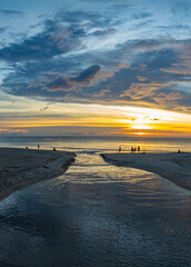The water from the canal flows to meet with the sea water..Golden sparkles in the sky shine in the water silhouette on the beach..The reflection of yellow sky shines on the beach.