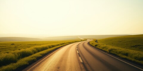 Fototapeta premium Asphalt road curving through a sunlit grassy landscape, offering a sense of journey and open road ahead