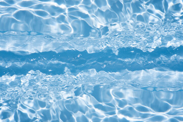 Blue water with ripples on the surface. Defocus blurred transparent blue colored clear calm water surface texture with splashes and bubbles. Water waves with shining pattern texture background.