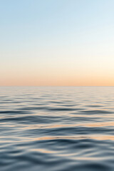 Obraz premium Tranquil ocean waves reflecting soft hues at sunrise over an endless horizon