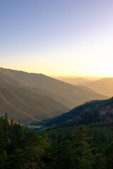 Forest covered mountain range with haze at sunset